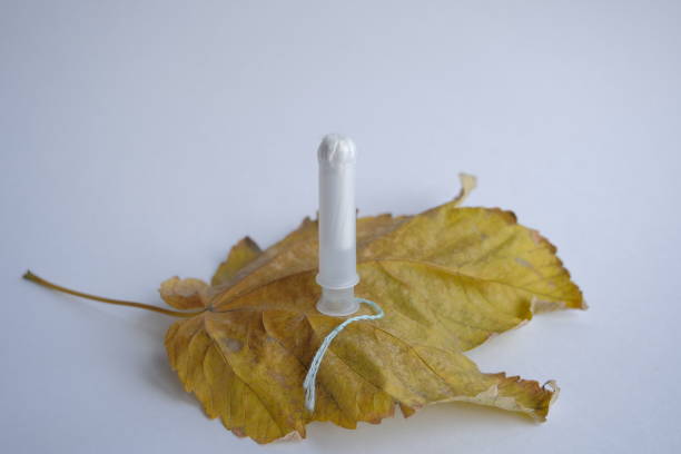 menopause concept. A female tampon lies on a yellow autumn leaf. tampon and fallen autumn leaf represent withered female beauty and the cessation of monthly menstrual cycles (menopause)