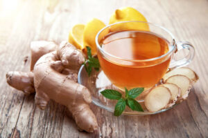 Ginger tea with lemon and mint in glass cup at old wooden board in rustic style.- slimming tea